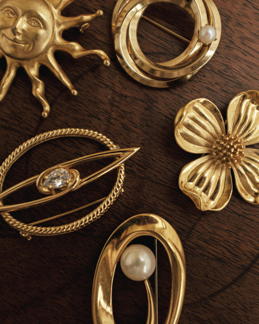 Collection of gold brooches on a wooden surface